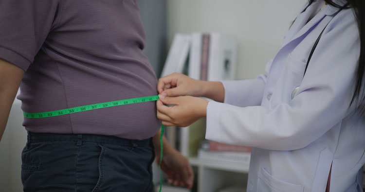measuring male patient's waistline with measuring tape