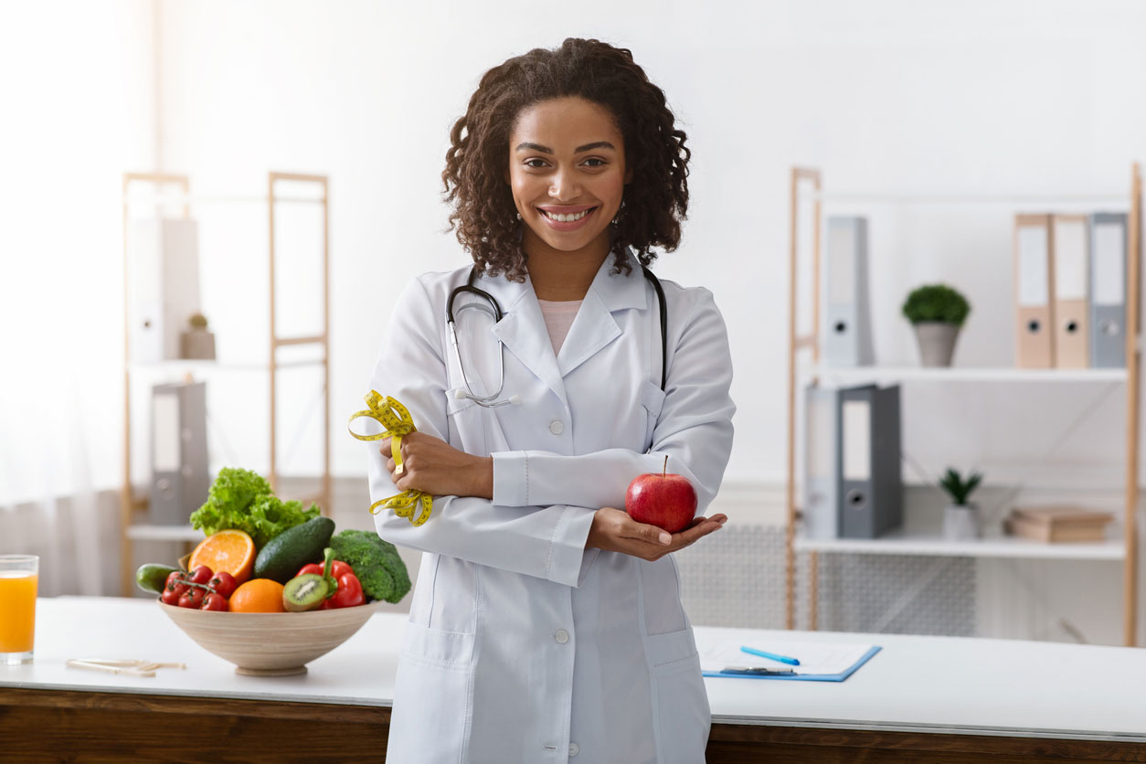 nutritionist holding an apple and a measuring tape